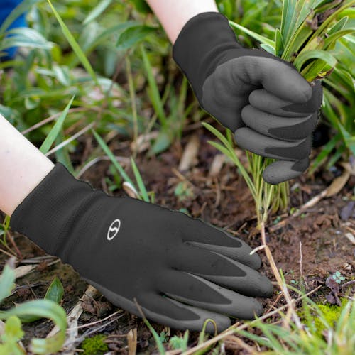Sun Joe 3-pack of Nitrile-Palm Reusable Black Gloves being used for planting in a garden,