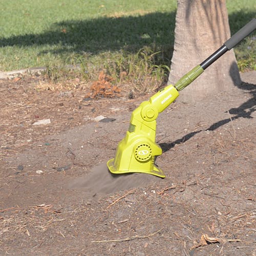 Sun Joe Electric Lawn Care System with the cultivator head being used to cultivate soil around a tree.