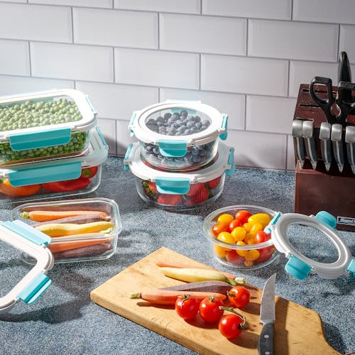 Containers from the EatNeat 20-Piece Set of 10 Superior Glass Food Storage Containers with airtight locking lids filled with food on a kitchen counter.