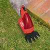 Sun Joe 2-in-1 Cordless red-colored Grass Shear and Hedger cutting grass.