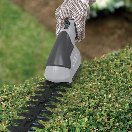 Sun Joe 7.2-volt Cordless Telescoping gray Grass Shear and Hedge Trimmer without the pole trimming a bush.