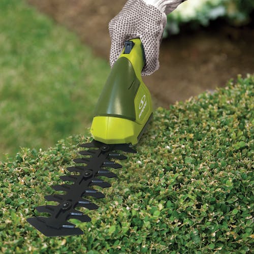Sun Joe 7.2-volt Cordless Telescoping green Grass Shear and Hedge Trimmer being used without the pole to trim a hedge.