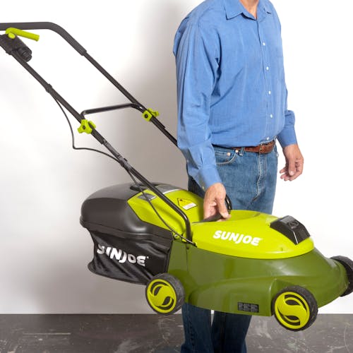 Man holding the Sun Joe 28-volt 5-amp 14-inch Brushless Cordless Lawn Mower by the handle on the body.