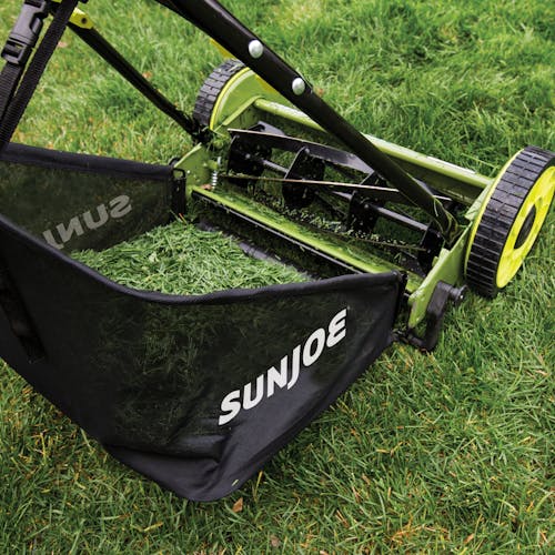Sun Joe 16-inch Manual Reel Lawn Mower with grass catcher filled with grass clippings.