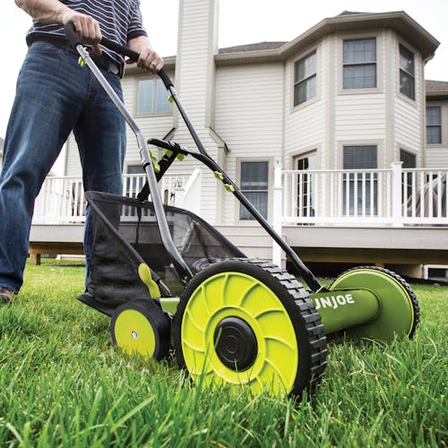 Sun Joe 18-inch manual reel mower with grass catcher being pushed across a lawn.