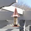 Martha Stewart Copper Bird Feeder with 4 ports filled with bird seed hanging from an overhead beam.