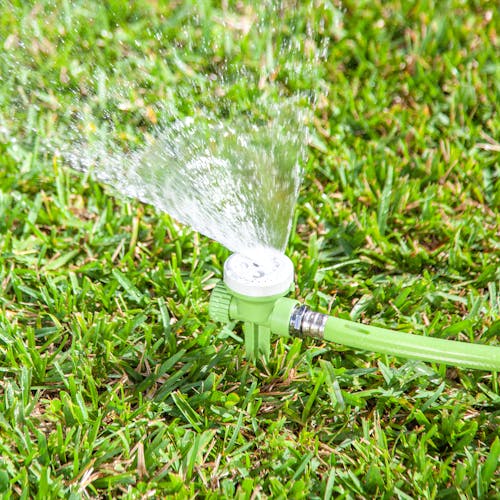 Martha Stewart 5-pattern Turret Sprinkler staked in the ground and watering a lawn.