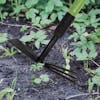 Close-up of the Martha Stewart Telescoping Cultivator and Hoe Combo on soil surrounded by plants.