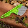 Nisaku Zassou Burush Tongari 3-inch Stainless Steel Angled Weeder outside next to rocks.