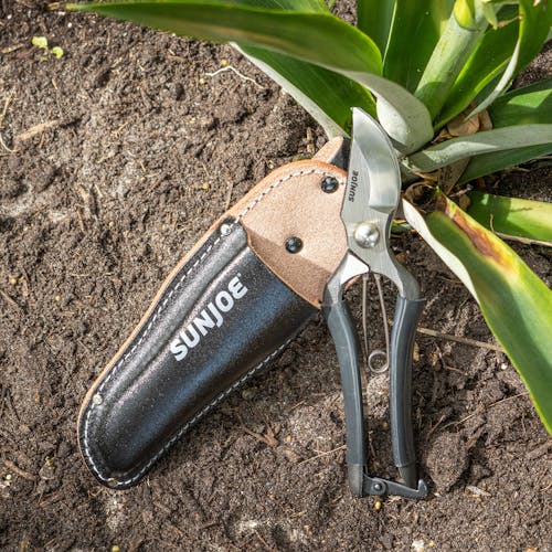 Nisaku Carbon Steel Pruner/Secateurs next to the leather holster in the dirt.