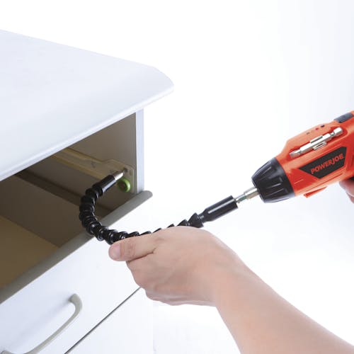 Person using the cordless screwdriver with the flexible bit extender to insert a screw in a drawer.
