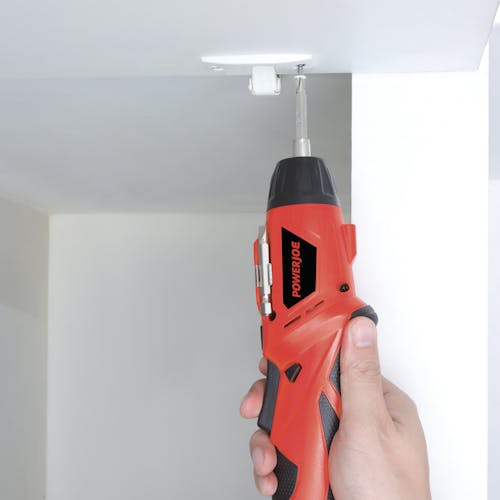 Person using the cordless screwdriver to insert a screw into the ceiling.
