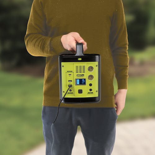 Person holding the Sun Joe 307Wh 6-Amp Portable Power Generator Station with a USB cord plugged in.