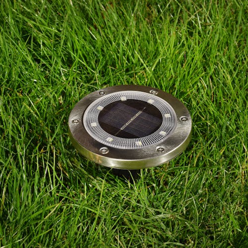 Metal disc pathway light staked in the ground.