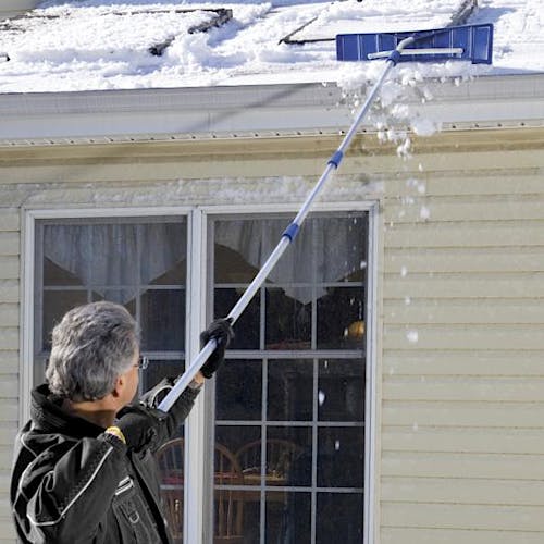 Snow Joe 21-foot telescoping snow shovel roof rake being used to get snow off the roof of a house.