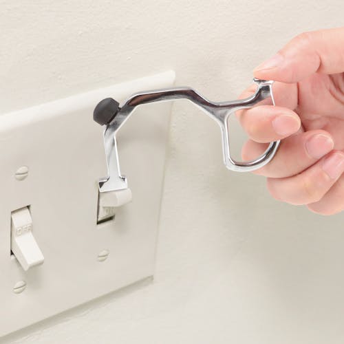 Person using the hand key tool to flip a light switch.