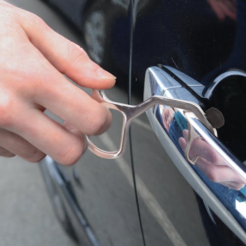 Person using the hand key tool to open a car door.