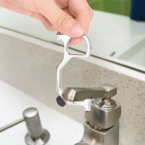 Person using the hand key tool to turn on a sink faucet.