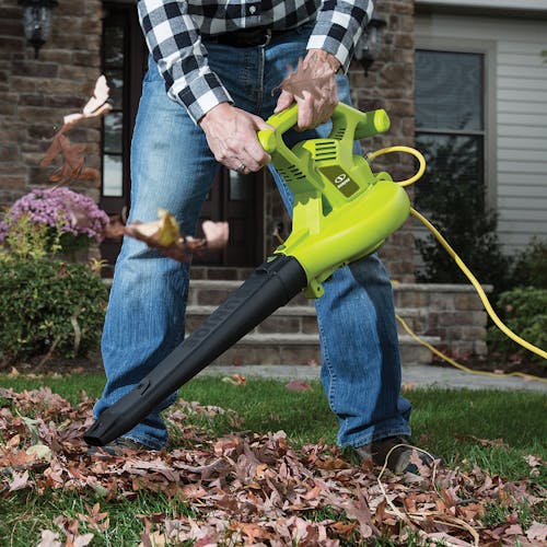 Sun Joe 13-amp 3-in-1 Electric Leaf Blower, Vacuum, and Mulcher blowing leaves off a lawn.