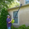 Person using the Sun Joe 14-amp high-performance 4-in-1 Electric Leaf Blower with the gutter attachment to blow leaves out of a gutter.