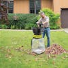 Man putting leaves into the Sun Joe 15-amp Bladeless Electric Leaf Mulcher and Shredder in a front lawn.