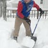 Snow Joe 18-inch Blue Shovelution Strain-Reducing Snow Shovel with spring assisted handle being used to throw snow off a patio deck.
