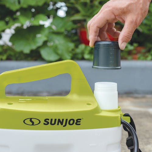 Person attaching the measuring cup to the Sun Joe 4-volt 1-gallon Cordless All Purpose Chemical Sprayer.