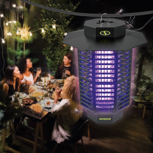 Sun Joe 18-Watt UV Indoor and Outdoor Bug Zapper hanging outside while a group of people eat around a table.