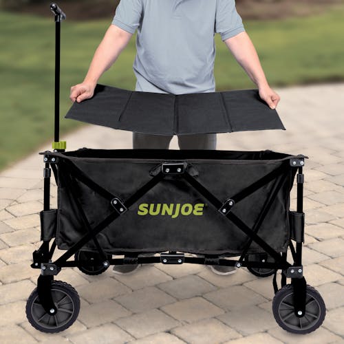 Person putting the base plate into the bottom of the Sun Joe Heavy-Duty Metal Framed Garden Utility Wagon.