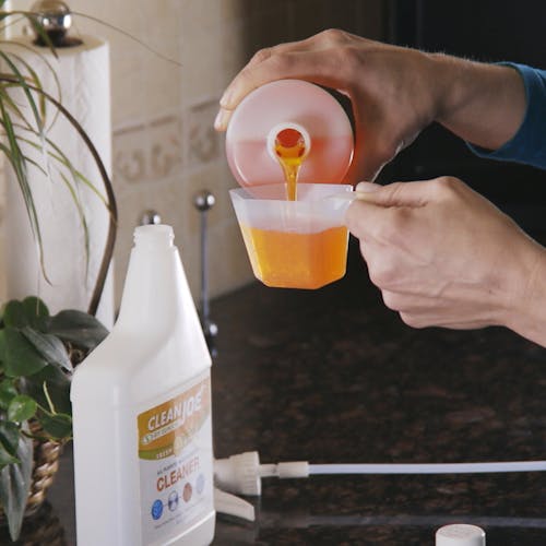 Person pouring the multi-surface cleaner into the measuring cup.