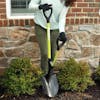 Sun Joe 9-inch Green Shovelution Strain-Reducing Utility Round-Point Digging Garden Shovel being used to dig a hole in a small garden.