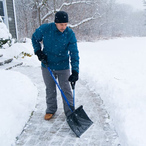 man shovelling snow off walkway with snow joe strain reducing shovel