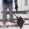 Snow Joe 20-inch Blue Shovelution Strain-Reducing Snow Shovel with spring assisted handle being used to clear snow off of front steps.