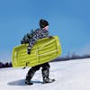 Kid carrying the Snow Joe 34-inch green-colored kids snow sled.