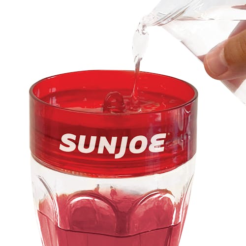 Close-up of the Sun Joe 40-ounce Wild Humming Bird Buffet Glass Feeder. being filled with nectar from the top.