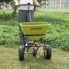 Sun Joe Multi-Purpose Walk-Behind Spreader being used to spread fertilizer on a lawn,