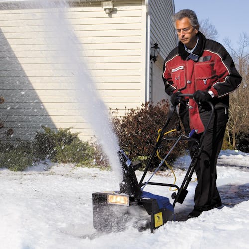Man making a pathway by blowing snow with the Snow Joe 15-amp 18-inch electric single-stage snow thrower.