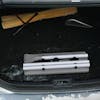 Snow Joe 2-pack of 4-in-1 telescoping gray-colored snow broom and ice scraper with LED light collapsed in the trunk of a car.
