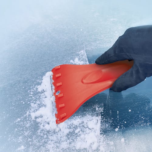 Snow Joe 4-in-1 telescoping red-colored snow broom and ice scraper scraping ice off a window.