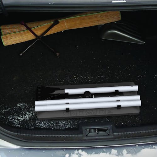 Snow Joe 18-inch 3-in-1 black-colored telescoping snow broom and ice scraper with an LED light collapsed in the trunk of a car.