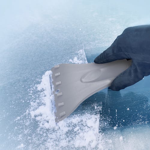 Snow Joe 18-inch 3-in-1 gray-colored telescoping snow broom and ice scraper with an LED light scraping ice off a window.