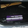 Snow Joe 18-inch 3-in-1 purple-colored telescoping snow broom and ice scraper with an LED light collapsed in the trunk of a car.