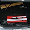 Snow Joe 18-inch 3-in-1 red-colored telescoping snow broom and ice scraper with an LED light collapsed in the trunk of a car.
