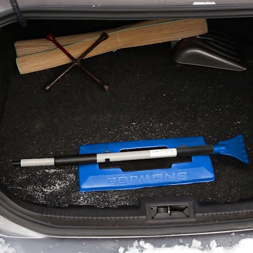 Snow Joe 19-inch 2-In-1 Telescoping Snow Broom and Ice Scraper collapsed and stored in the trunk of a car.