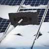 Snow Joe 19-inch 2-In-1 Telescoping black Snow Broom and Ice Scraper being used to push snow off of solar panels.