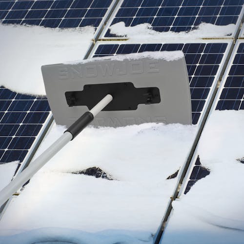 Snow Joe 19-inch 2-In-1 Telescoping gray Snow Broom and Ice Scraper being used to push snow off of solar panels.