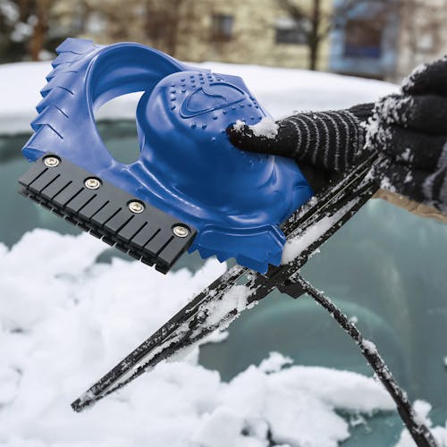 Snow Joe Ice Dozer Ice and Snow Scraper Tool with Squeegee Brush being used to get snow off a windshield wiper.