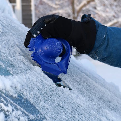 Person using the Snow Joe ice dozer snow and ice scraper to scrape ice off a car windshield.