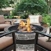 Fire going in the Sun Joe 35-Inch Charcoal stone Cast Stone Base, Wood Burning Fire Pit with patio chairs around it.