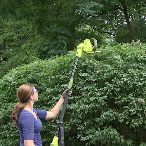 Sun Joe 4-amp 21-inch Electric Telescoping Pole Hedge Trimmer being used to trim a bush.